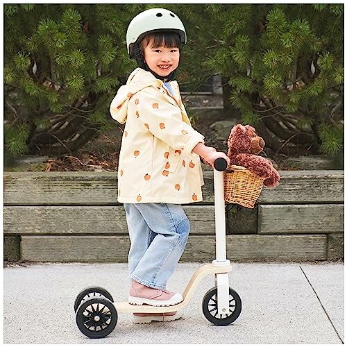 Child on a scooter with a helmet and teddy bear in basket.