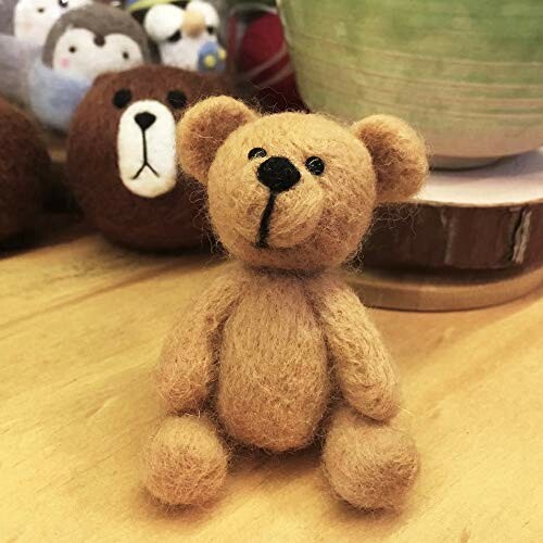 Handmade felt teddy bear on wooden surface