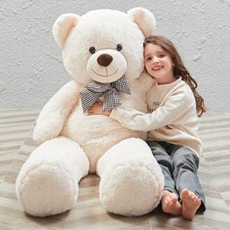 Child hugging a large white teddy bear.